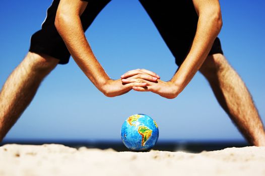 Earth globe on the beach and hands over it. Ideal for Earth protection concepts, recycling, world issues, enviroment themes