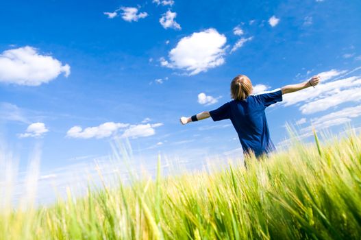 Happy man with arms up on summer field