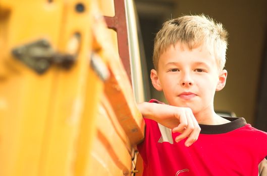 Young boy lean on yellow truck