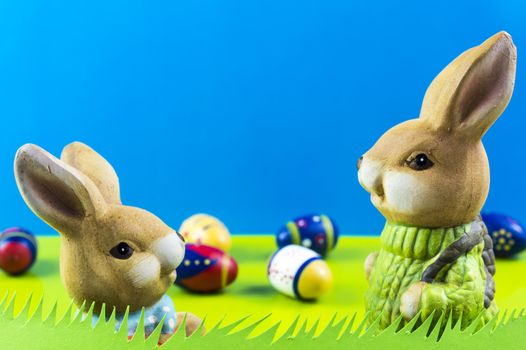 Easter bunnies playing on grass on blue background