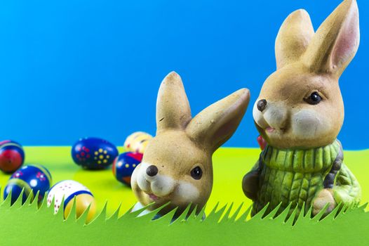 Easter bunnies playing on grass on blue background