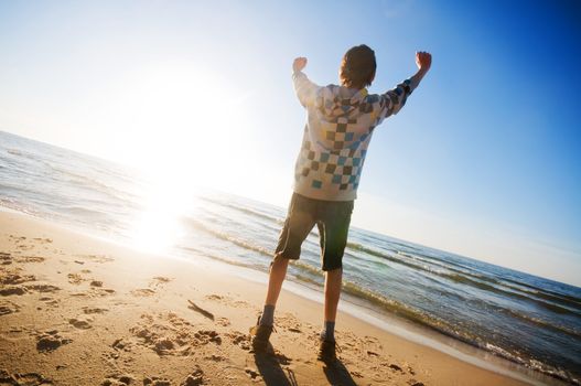 Happy boy jumping for joy at the beach