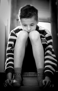 Portrait of young boy sitting sadly
