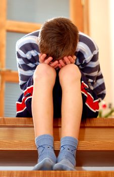 Portrait of young boy sitting sadly