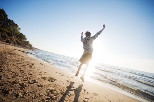 Happy boy jumping for joy at the beach