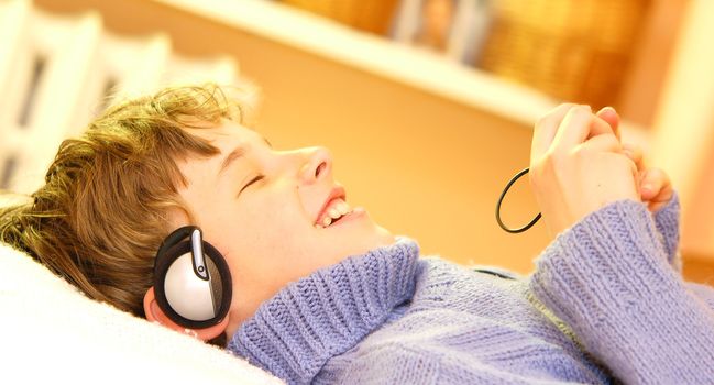 Boy listen to music in warm sunny bedroom