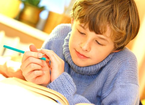 Boy doing homework on bed in sunny bedroom