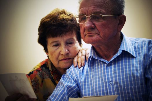 Senior couple looking at old photographs. Reminisce about the past