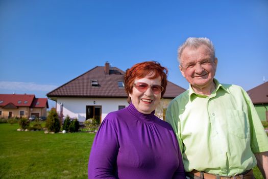 Senior smiling couple in front of their new house