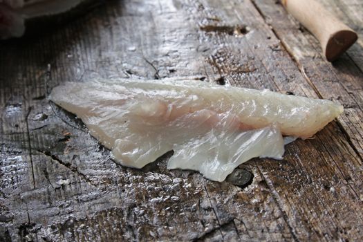 A fillet from a freshly cleaned Largemouth Bass sitting on an outdoor cleaning board.
