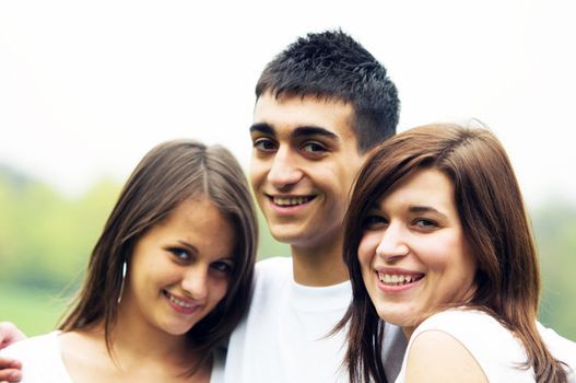 Three young happy friends standing together and smiling