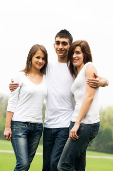 Three young happy friends standing together and smiling