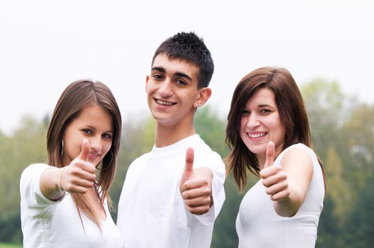 Three young happy friends laughing and giving okey sing