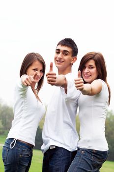 Three young happy friends laughing and giving okey sing