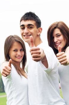 Three young happy friends laughing and giving okey sing