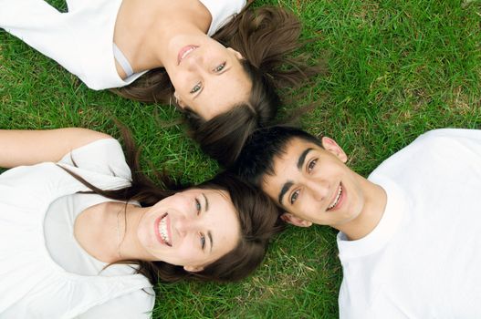 Three young happy friends lying together and laughing. Top view