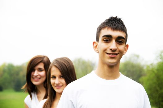 Group of teenagers standing and smiling. Boy in the foreground