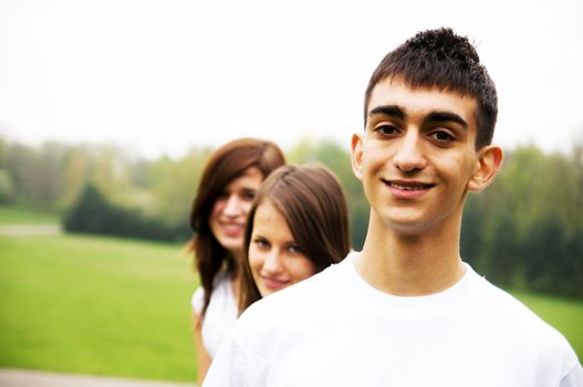 Group of teenagers standing and smiling. Boy in the foreground