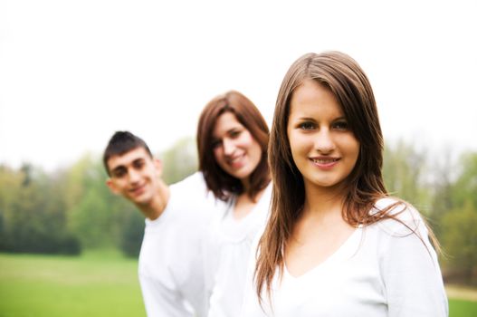Group of teenagers standing and smiling. Girl in the foreground