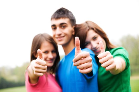 Three young happy friends laughing and giving okey sing