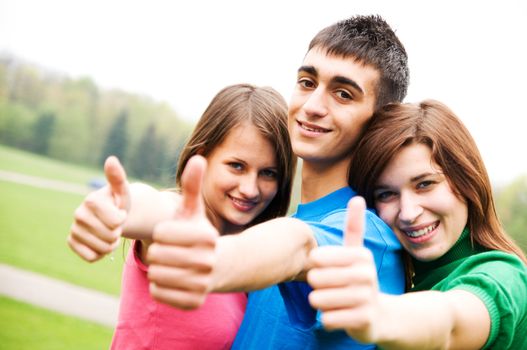 Three young happy friends laughing and giving okey sing