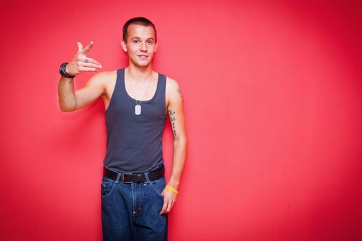 Young handsome man standing in a sexy pose on red background