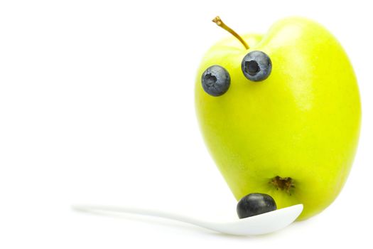 joke apple with eyes and a spoon with blueberries isolated on white