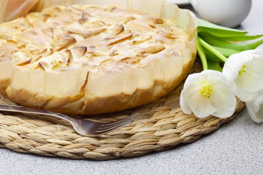 apple pie, fork and tulips on a woven mat