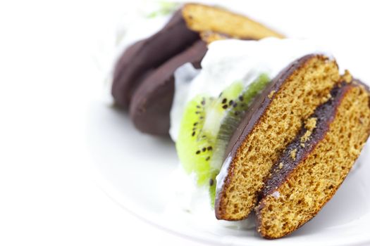 cake with cream and kiwi fruit on a plate isolated on white