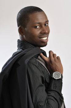 Portrait of young successful fashionable businessman holding jacket over shoulder on grey background