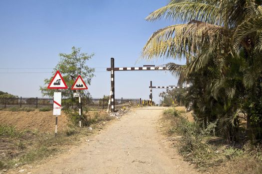 Landscape taken in Gujarat India of a typical Indian railway crossing in the hinterlands of India. No barriers and generally the gravel road is used by bullock carts and public to access their farms or work places.