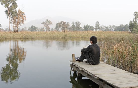 man sitting on a wooden pier