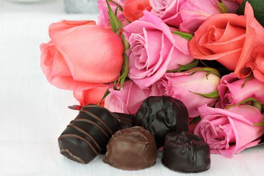Delicious chocolate candies with a bouquet of roses. 