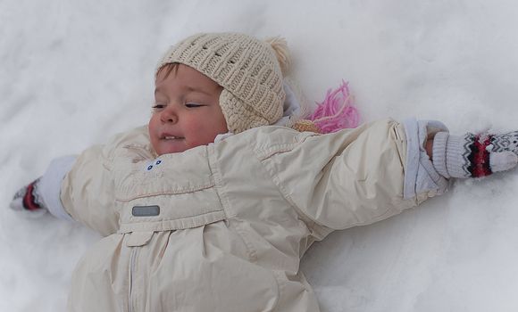 Little girl lays on the snow