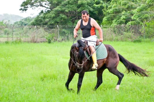 Men on horseback in the rain on a farm in Ecuador