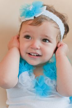 Little girl in the blue dress closes her ears