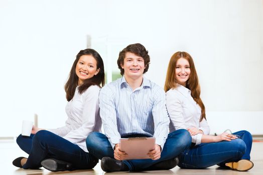 portrait of a group of young people sitting on the floor, man and two attractive women