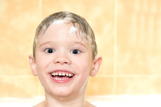 child washing in the shower with a foam on the head 