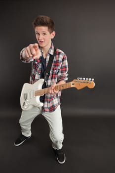 Photo of a teenage male playing a white electric guitar and pointing at you.