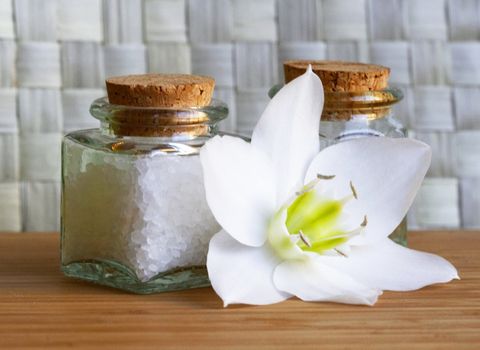 Bottles of sea salt and oil with white flower in spa composition 