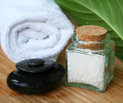 White bath towel, bottle of sea salt and stones in spa composition 

