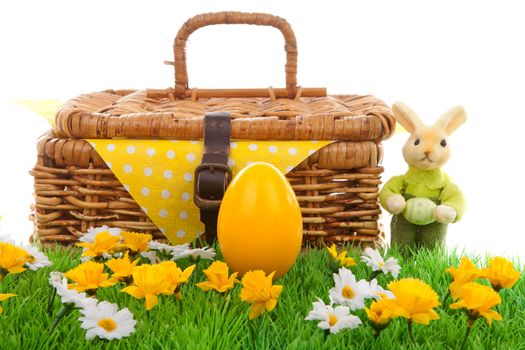 Yellow easter egg, bunny and basket on green grass with flowers