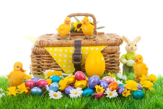 Colorful easter eggs, bunny, chickens and basket on green grass with flowers