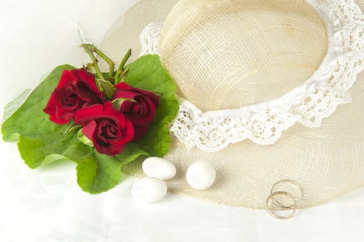 a  red roses and wedding rings on white background