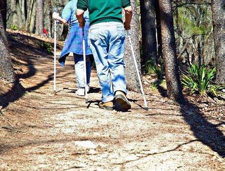 A man and woman walking with poles on a trail.