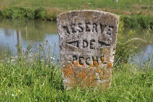 Stone sign post by a river