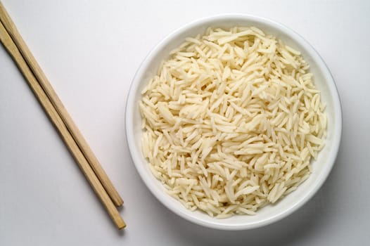 Dish of Basmati rice and chopsticks seen from above over white background 