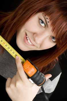 Beautiful redhead girl using measuring tape in workshop and pointing at 25cm to allude to the length of male reproductive organ, penis. Ironic.

Studio shot.