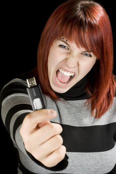 Beautiful redhead girl holding an usb memory stick or flash drive at the camera with an angry expression.

Studio shot.