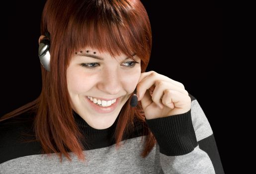 Beautiful smiling girl at a call center answering with a handset.

Studio shot.
